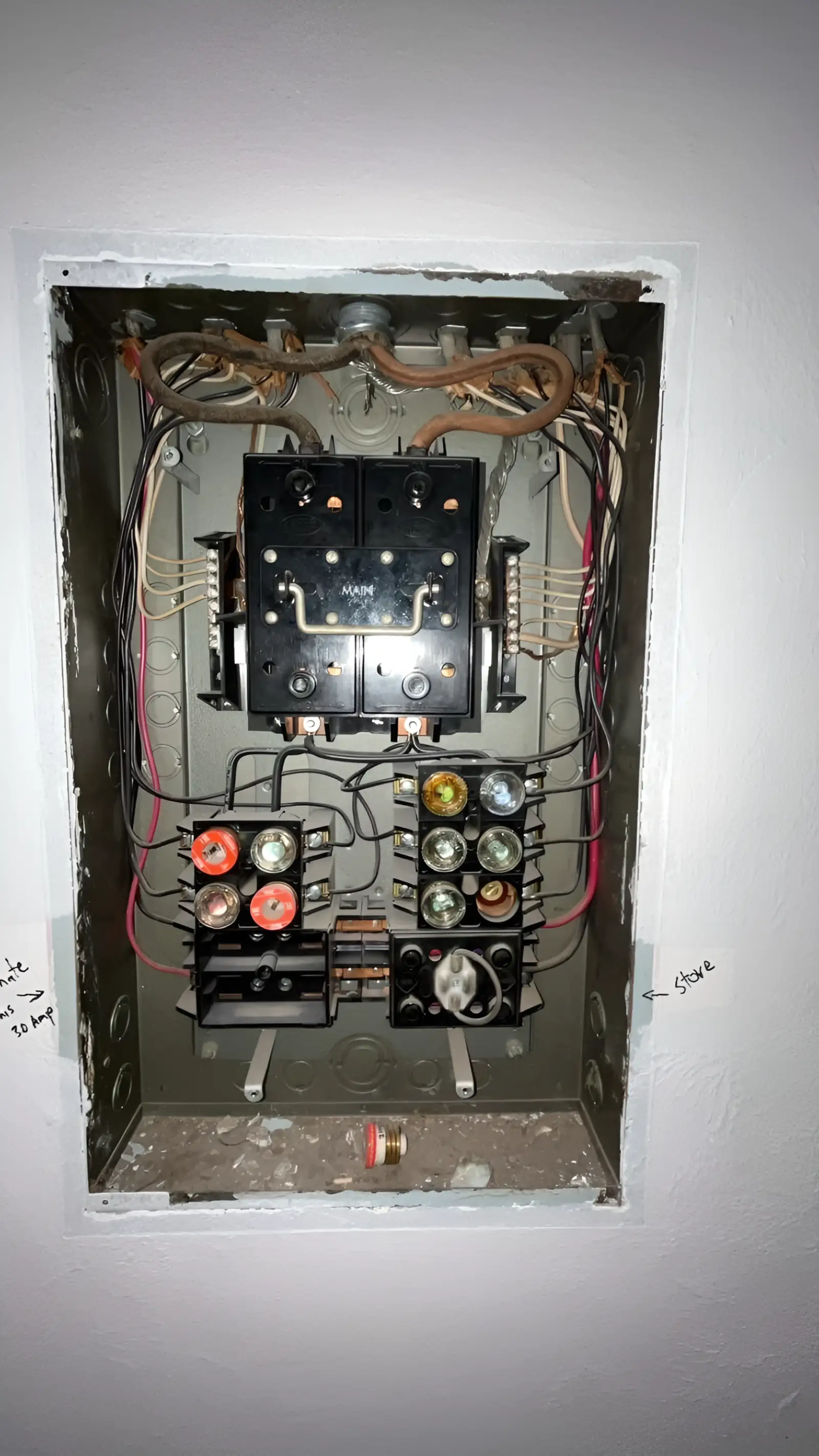 The antique screw-in-fuse main box that was removed, its cloth-covered conductors and pull-out fuse blocks exposed in the wall.